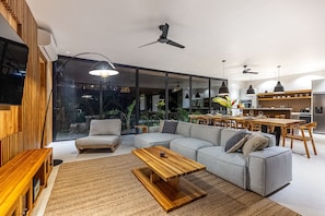 Uma sala moderna com sofá seccional, mesa de centro de madeira e área de jantar com mesa e cadeiras de madeira.