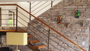 Ein modernes Wohnzimmer mit einer Steinwand, einer Holztreppe, einem Sofa und einem Couchtisch.