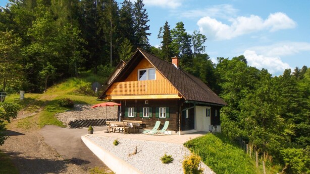 A wooden house with a sloped roof, a balcony, and a gravel driveway. - Ferienhaus mit Landblick (Oberhaag)