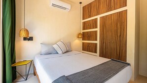 Une chambre à coucher avec un lit, une armoire en bois, un climatiseur, une lampe de chevet et un rideau vert.