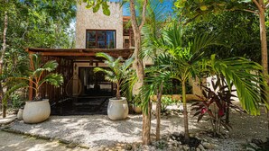 Un bâtiment moderne à la façade en pierre, entouré d’une végétation tropicale luxuriante.
