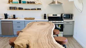 A modern kitchen with a central island, bar stools, a microwave, and a decorative deer head. - Stardust on the Mesa...A Breathtaking Experience (Yucca Valley)