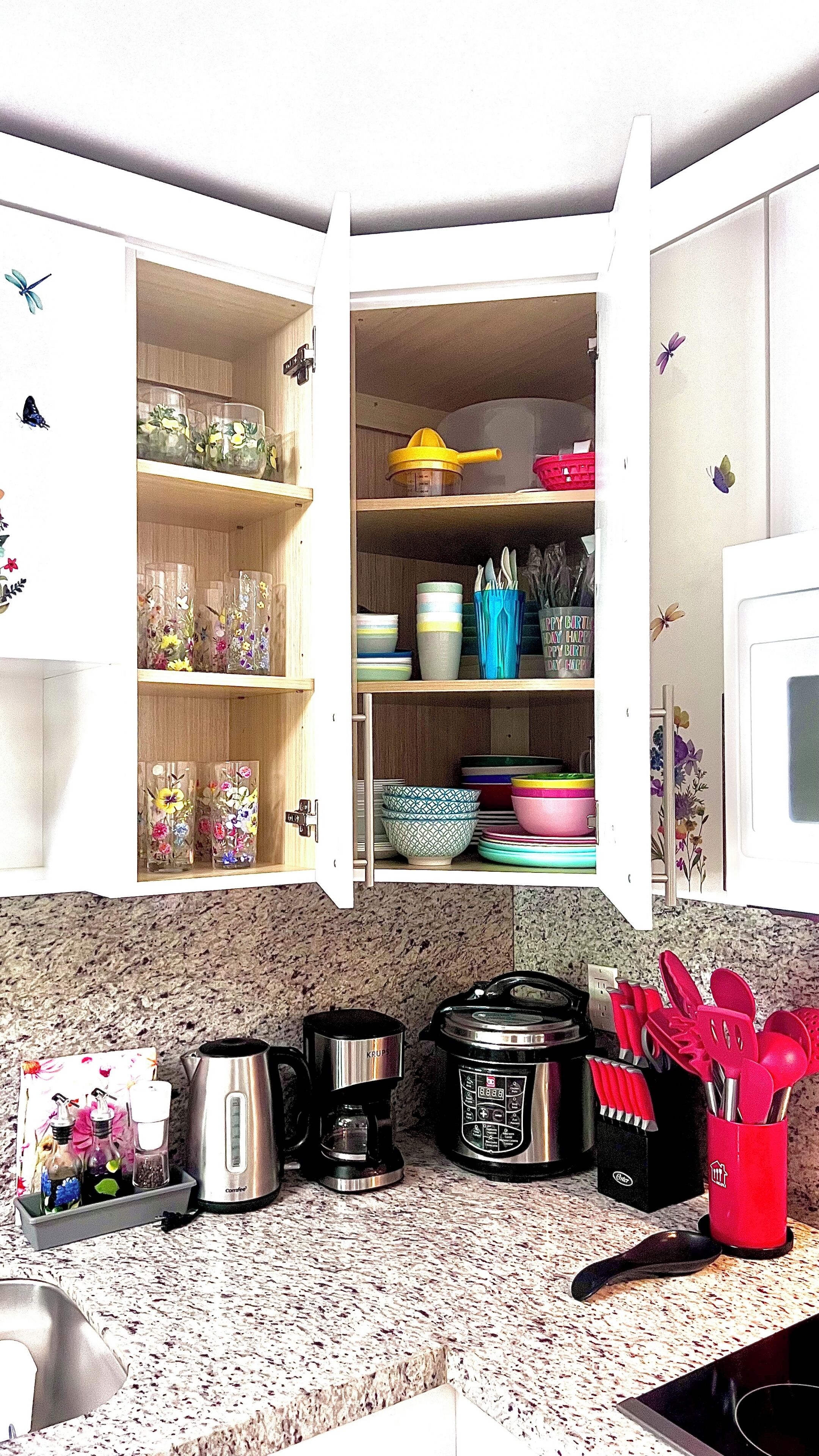 A kitchen with open cabinets displaying various dishes and utensils.