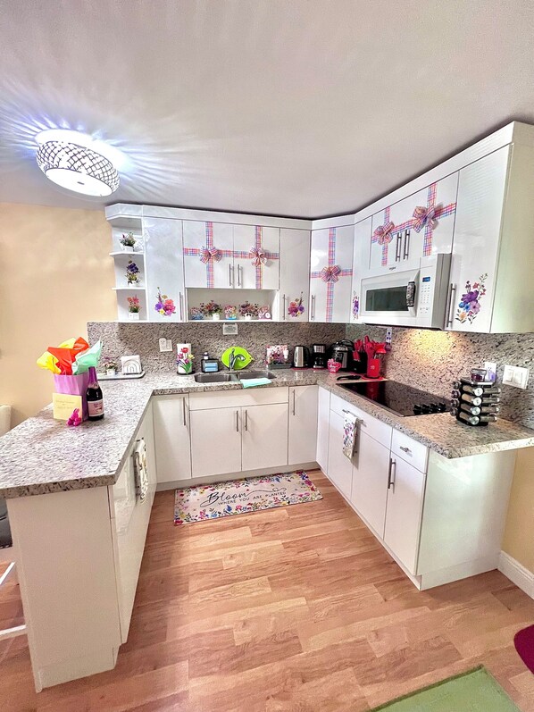 A kitchen with white cabinets, a microwave, and a sink. - Boutique Guest House – Private Patio Oasis – Near Beach – Family-Friendly (North Miami)