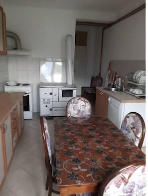 A compact kitchen with a dining table, white cabinets, and a tiled backsplash. - Quiet rest, pristine river&cafes (Danilovgrad)