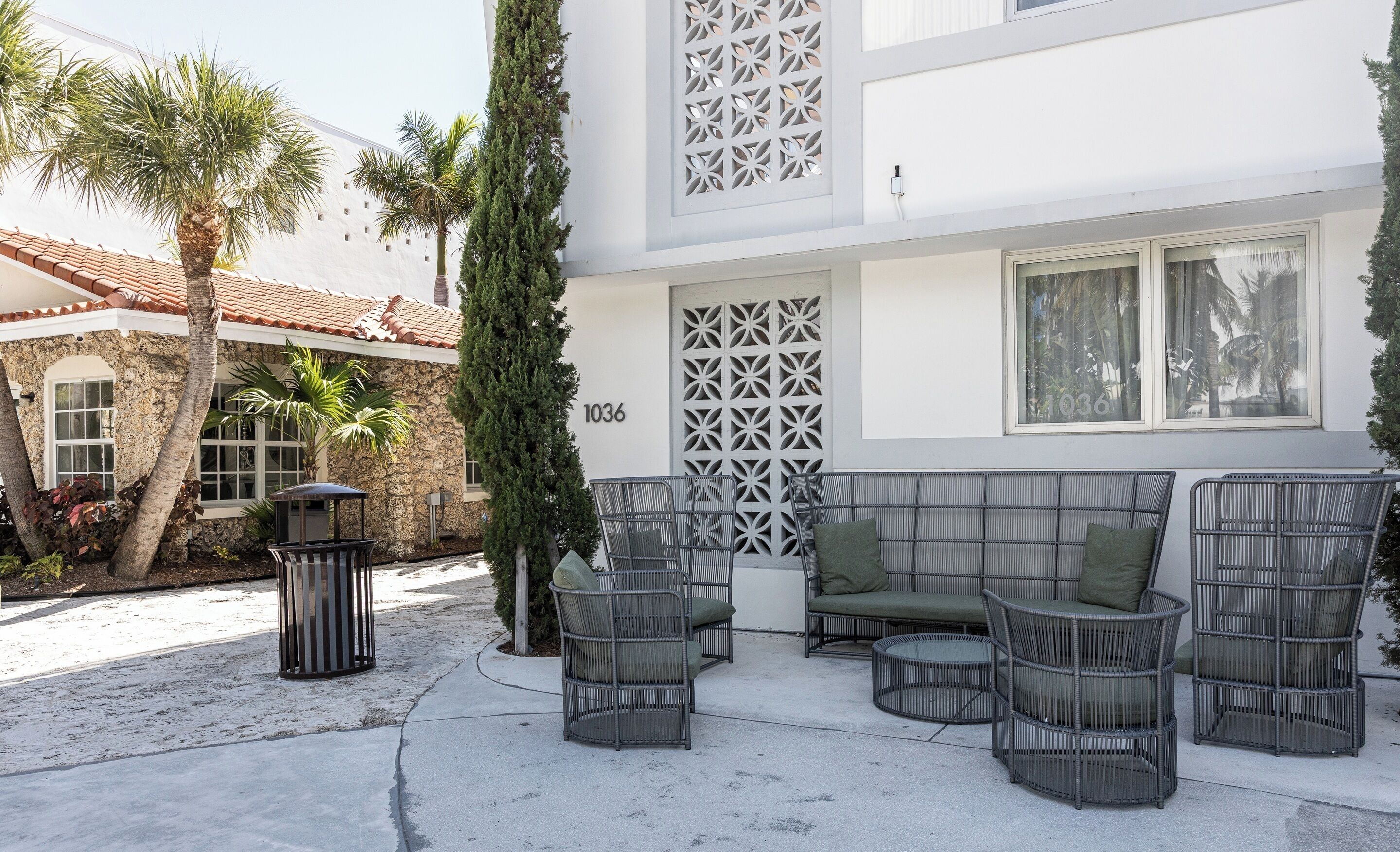 A courtyard with outdoor seating, a stone wall, and a building with a numbered door.