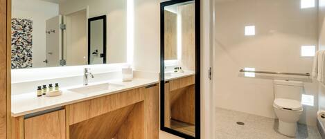 A modern bathroom with a wooden vanity, a large mirror, and a toilet.