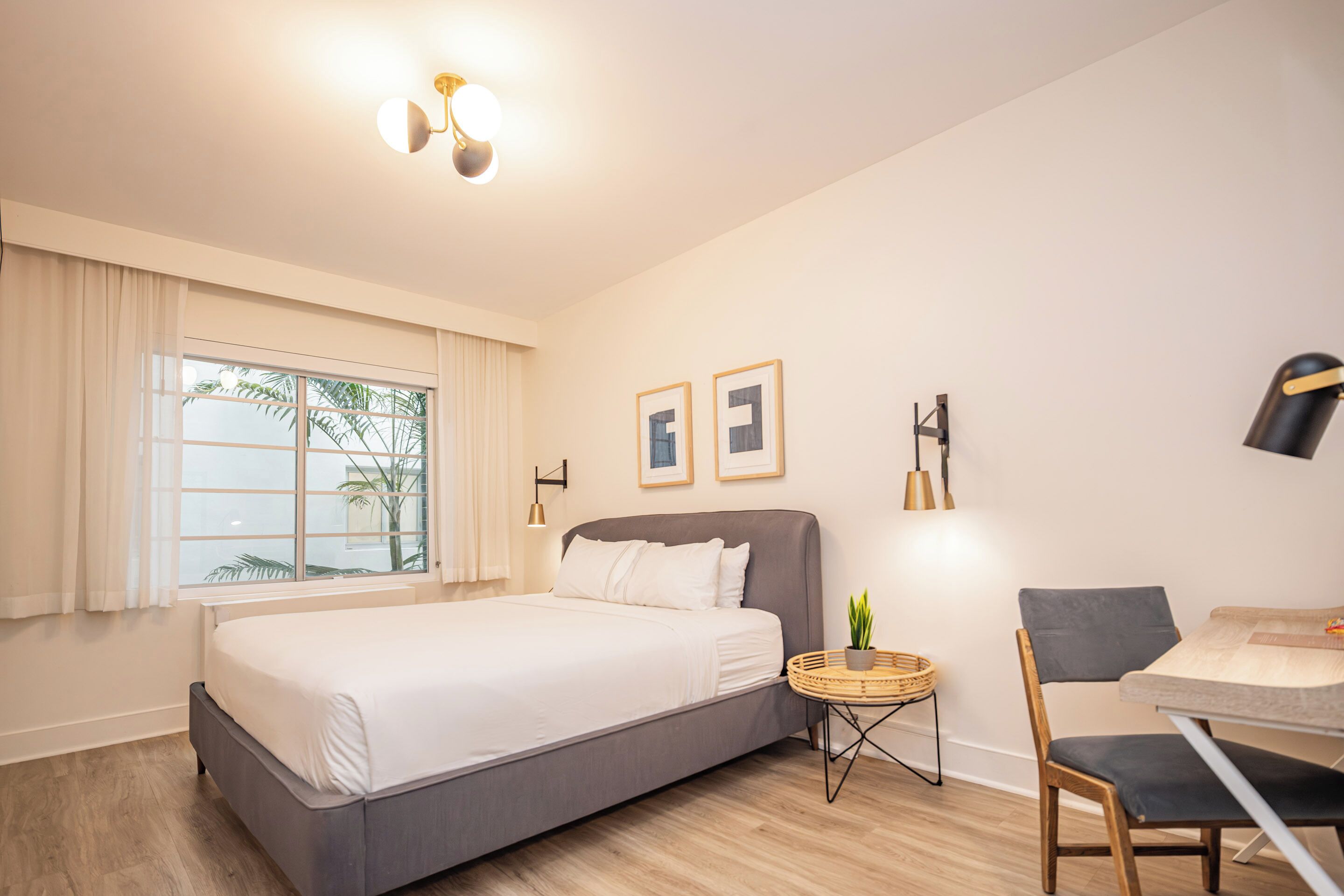 Une chambre d’hôtel moderne, dotée d’un grand lit, d’un bureau et d’une chaise.