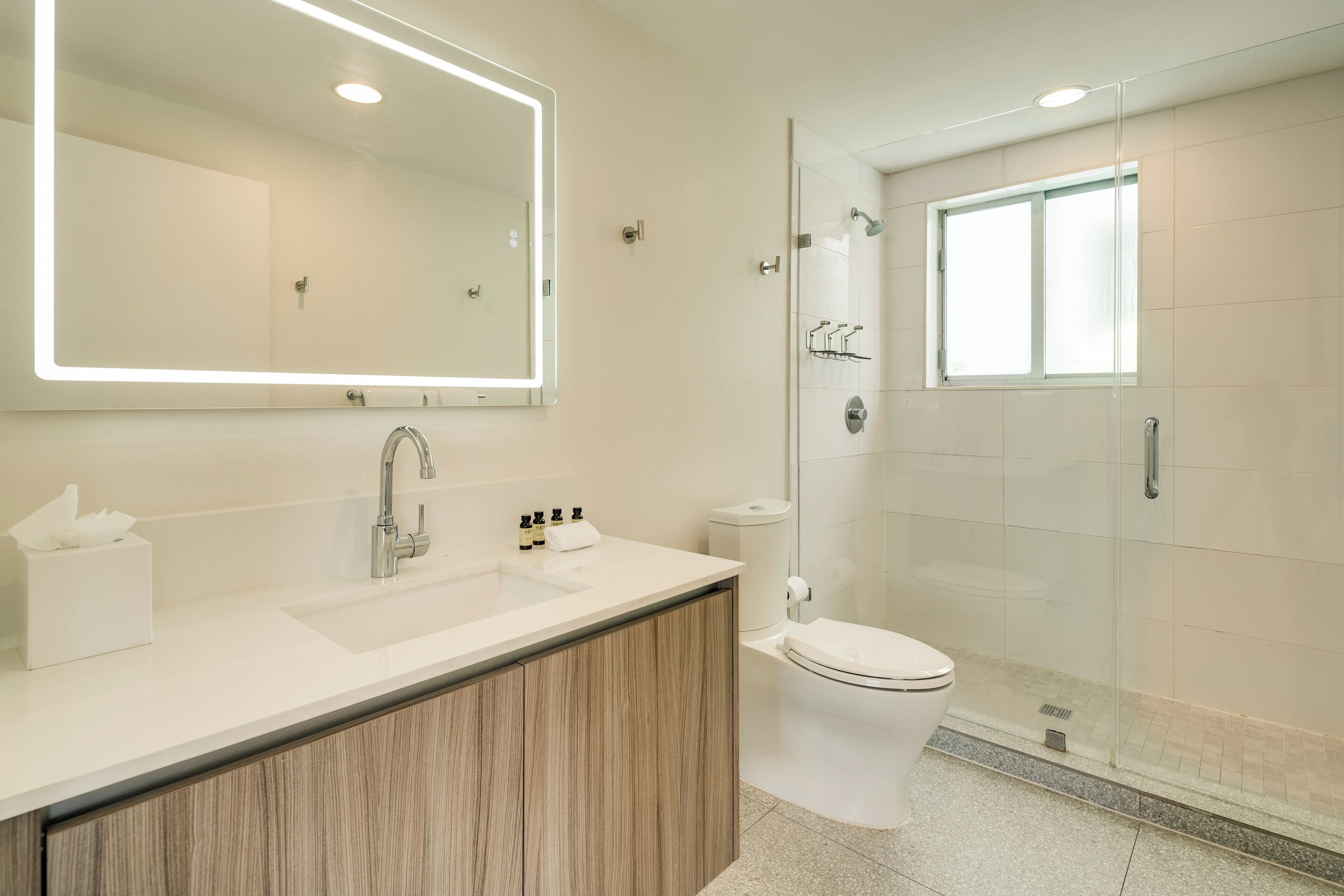 A modern bathroom with a large mirror, sink, and toilet.