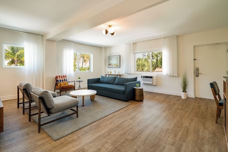 A spacious living room with a sofa, armchairs, a coffee table, and a dining area.
