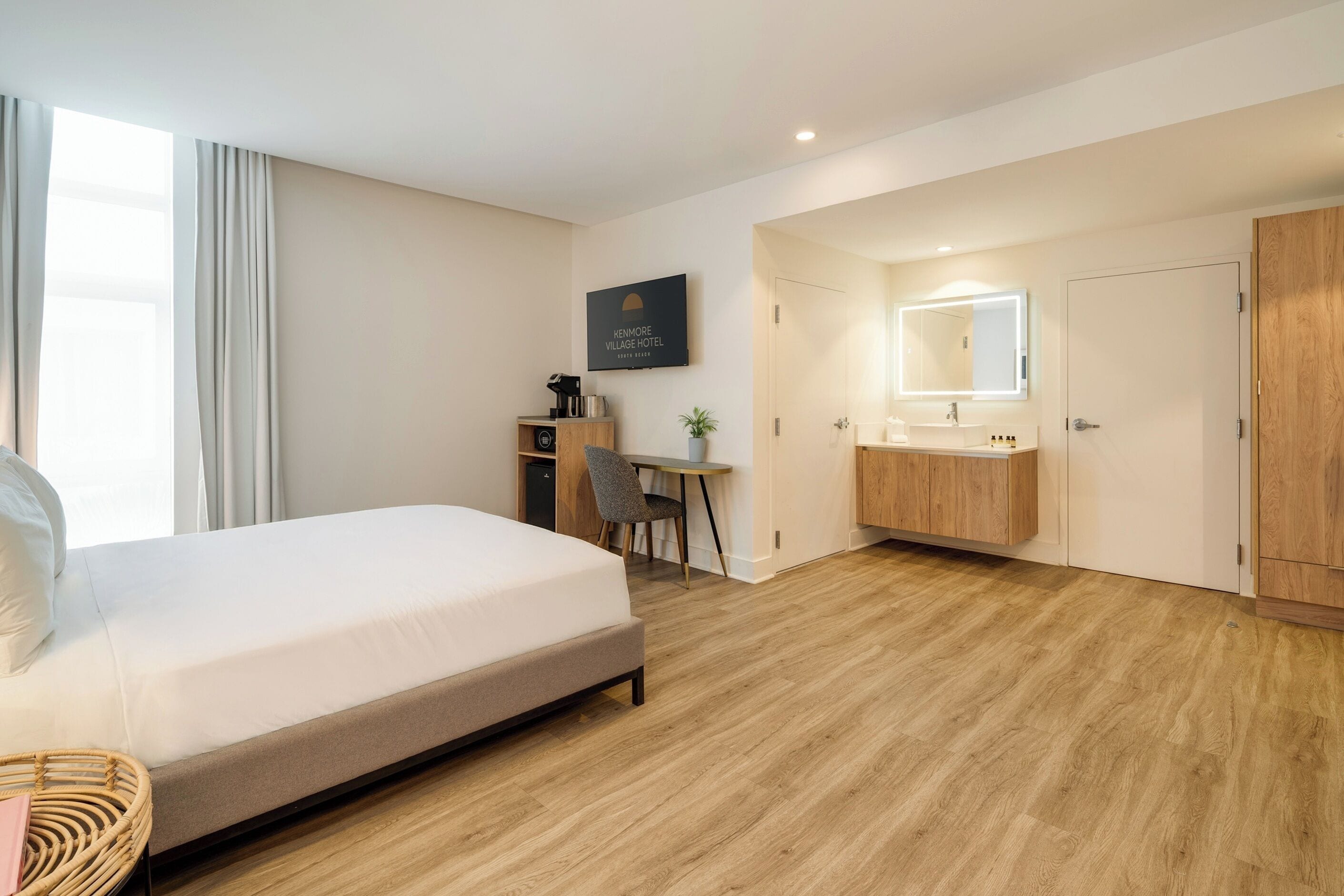 Una habitación de hotel moderna con cama, escritorio, silla y tocador con espejo.