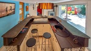 Une cuisine moderne dotée d’un îlot central, de tabourets de bar et d’une grande fenêtre offrant une vue sur l’extérieur.