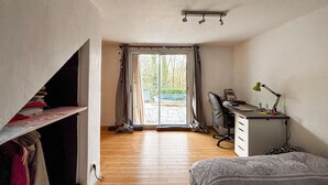 Une chambre à coucher avec un lit, un bureau, une chaise et une fenêtre avec des rideaux.