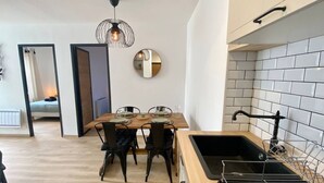 Una cocina moderna con encimera de madera, pileta negra y lámpara colgante.