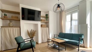 Una sala de estar moderna con sofá, sillón, mesa de centro, televisor y plantas decorativas.