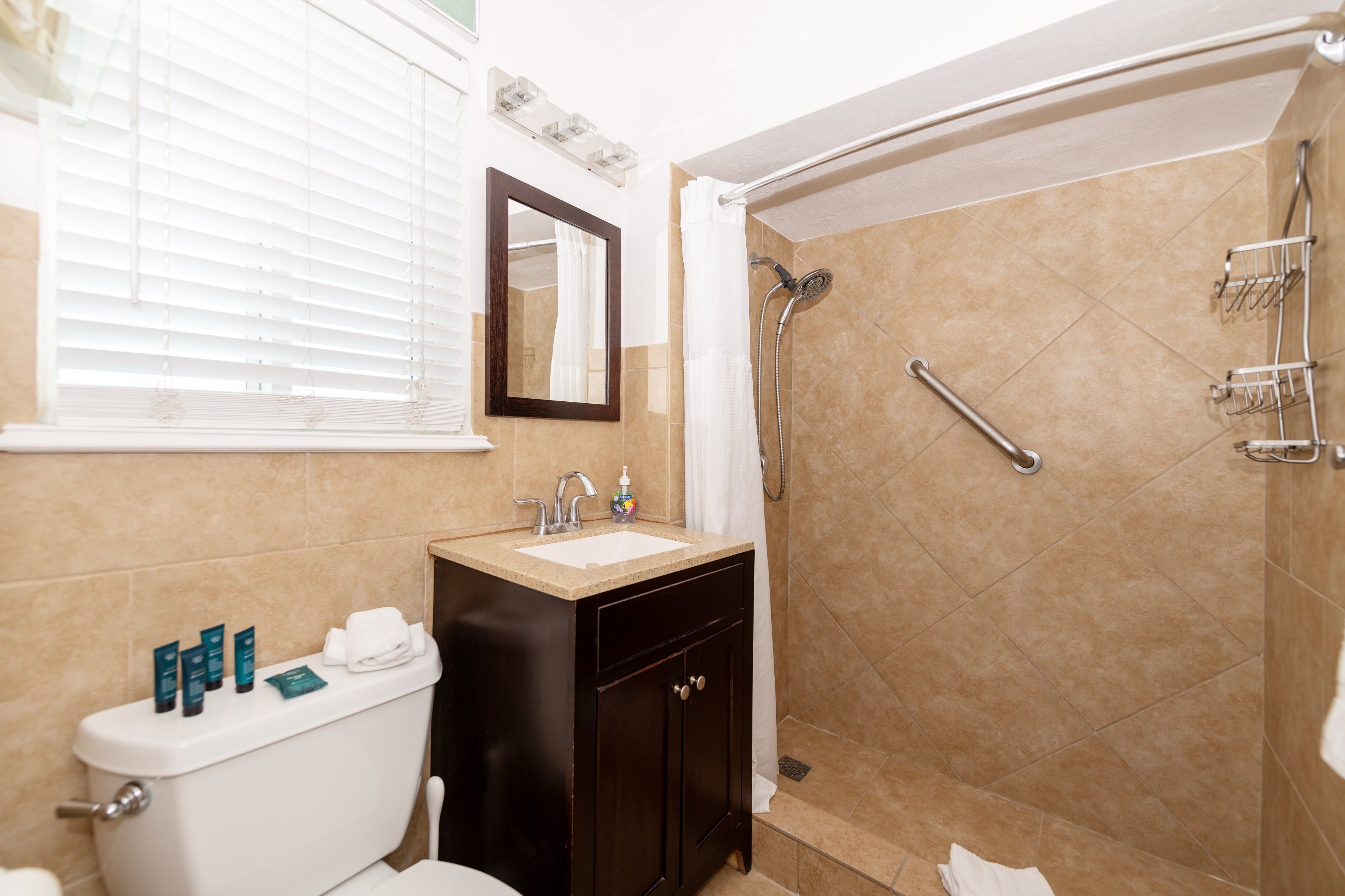 Une salle de bain équipée d’un WC, d’un lavabo, d’un miroir, d’une douche et d’un porte-serviettes.