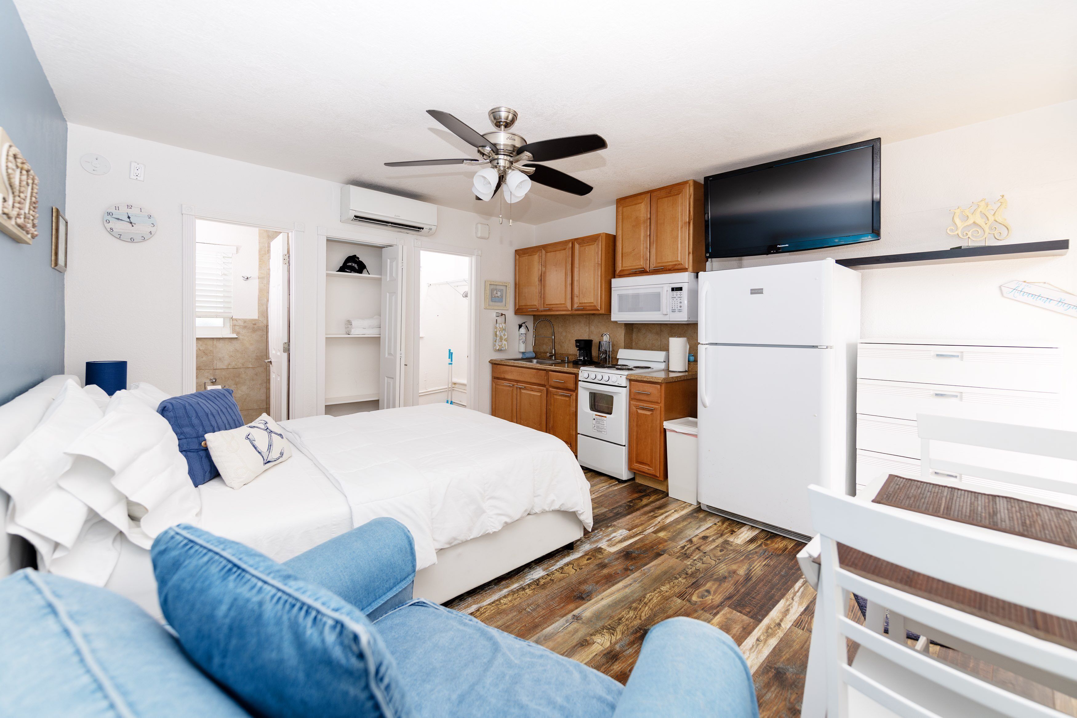 Un espace de vie compact comprenant un lit, une kitchenette et un ventilateur de plafond.