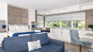 A modern bedroom with a large bed, a sofa, and a dining area with a view of the outdoors. - Tropic Isle Boutique Hotel  (Hollywood)