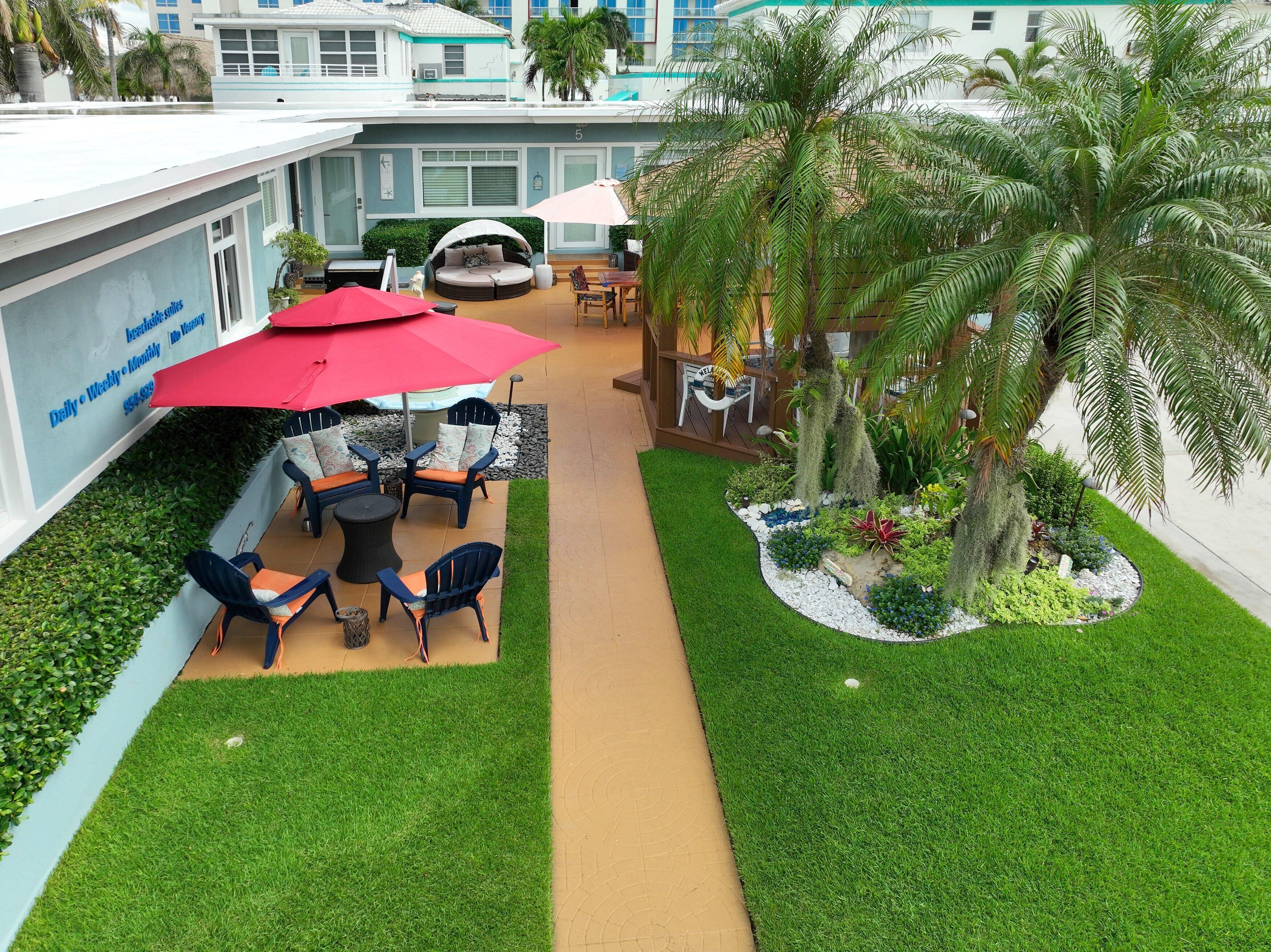 Un patio con zona de estar, palmeras y césped cuidado.