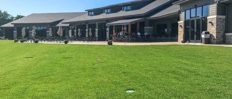 A building with a covered patio area, outdoor seating, and a well-maintained lawn.