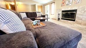 A living room with a sectional sofa, a coffee table with a tray, and a fireplace. - Lake Arrowhead Retreat with club pools and beaches (Nekoosa)