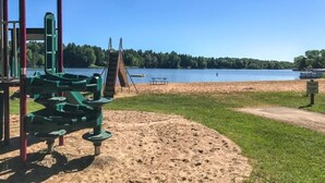A playground with a slide and climbing structures near a sandy beach by a lake. - Lake Arrowhead Retreat with club pools and beaches (Nekoosa)