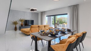 A modern dining area with a large table set for a meal, a sofa, and a TV against a grey wall. - Stunning home in Barban (Barban)