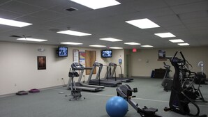 Ein Fitnessstudio mit Laufbändern, Crosstrainern und Gymbällen.