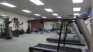 Et fitnesscenter med løbebånd, crosstrainere og træningsbolde.