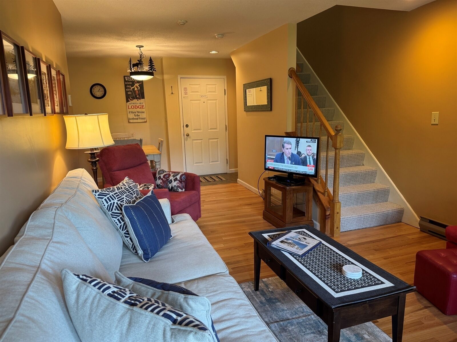 A living room with a sofa, armchair, TV, and a staircase.