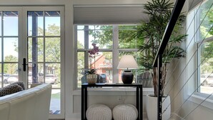 Un salon moderne avec un canapé, une console agrémentée d’objets décoratifs et de grandes fenêtres offrant une vue sur l’extérieur.