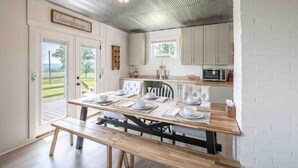 A dining area with a wooden table set for four, a bench, and a view of the outdoors through a door. - 4K Ranch - 10 acre property & home near Hermann (New Florence)