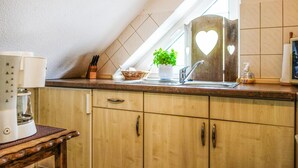 A kitchen with wooden cabinets, a sink, a potted plant, and a heart-shaped cutout on the wall. - Gorgeous apartment in Otterndorf (Otterndorf)