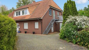 A two-story house with a red-tiled roof, a brick exterior, and a small front garden. - Gorgeous apartment in Otterndorf (Otterndorf)