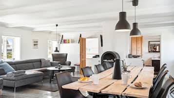 Une cuisine moderne avec un coin repas, comprenant une grande table en bois, des chaises noires et des luminaires suspendus.