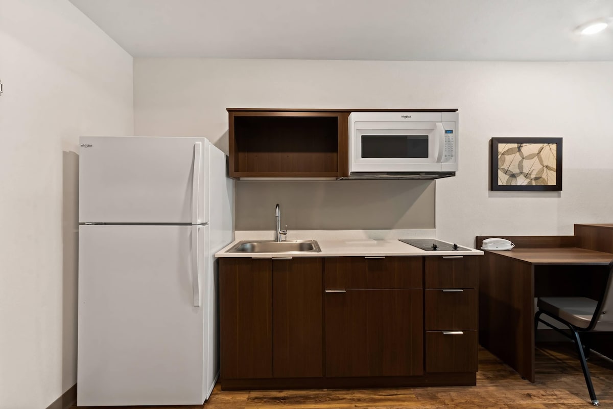 A compact kitchen with a white refrigerator, a microwave, and a sink.