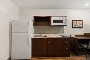 Cocina compacta con un refrigerador blanco, un microondas y un lavamanos.
