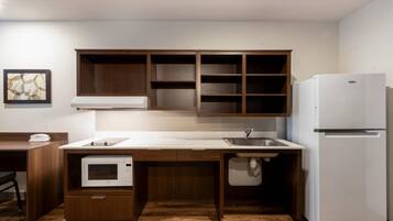 A compact kitchen with a built-in microwave, a refrigerator, and a sink.
