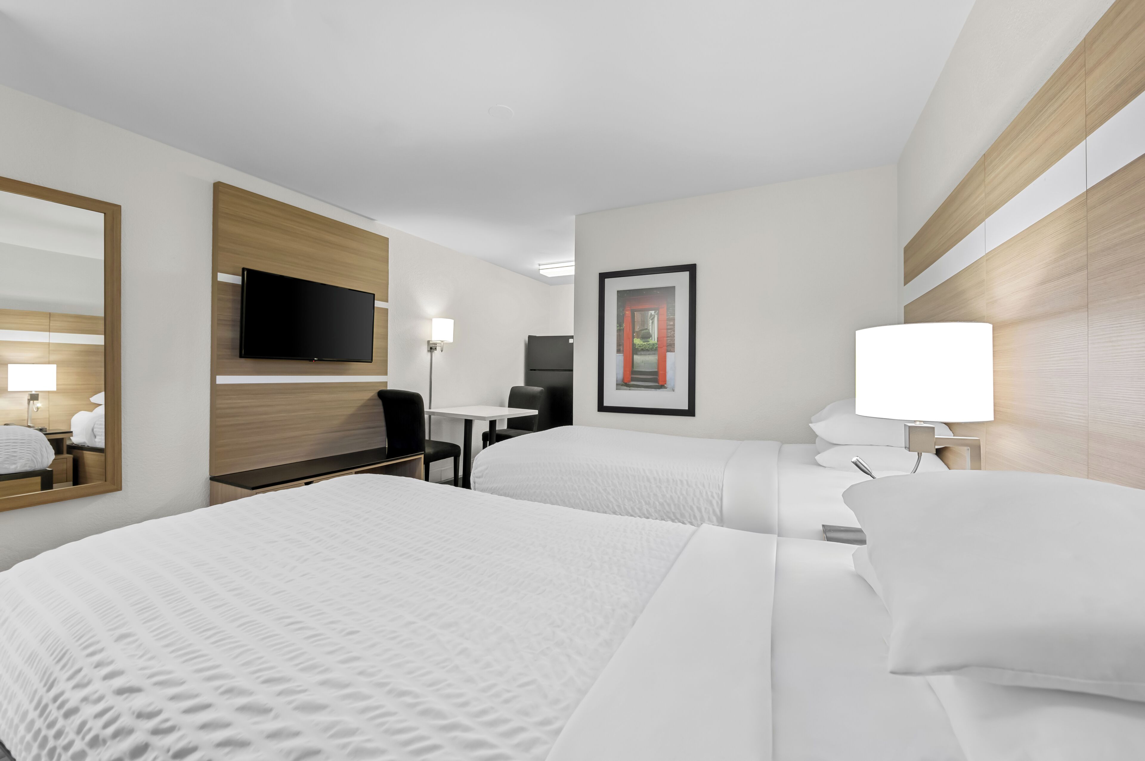 A hotel room with two beds, a flat-screen TV, a desk, and a chair.