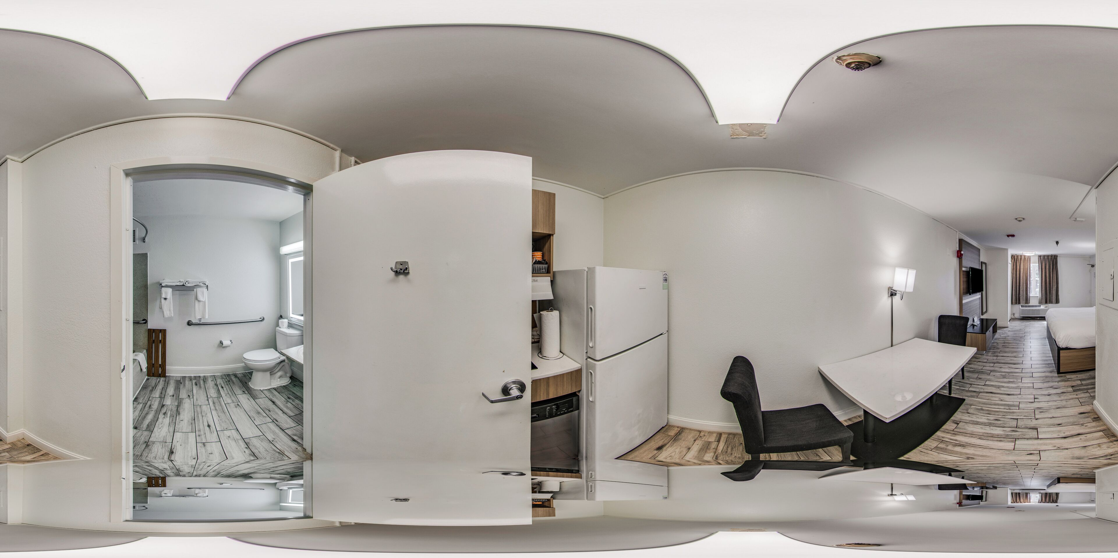 A modern interior with a white color scheme, a kitchen area, a dining space, and a bathroom with a herringbone floor pattern.