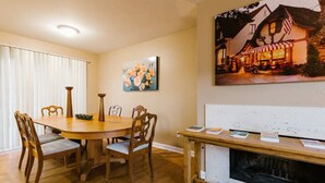 Un comedor con una mesa y sillas de madera, un cuadro de flores y una chimenea con repisa.