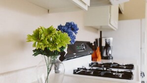 Una cocina con un florero de vidrio transparente que contiene flores verdes y azules sobre la encimera.