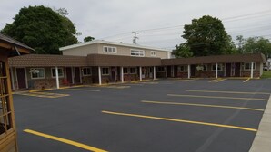 Un motel con estacionamiento, varias habitaciones y un pequeño jardín.
