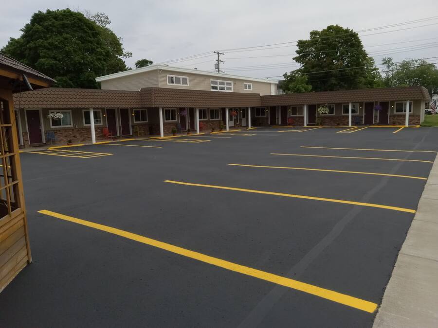 A motel with a parking lot, multiple rooms, and a small garden area.