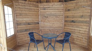 Una cabaña de madera con una mesa redonda y dos sillas.