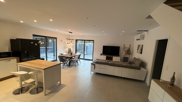 A modern kitchen with a dining area, a living room with a sofa, and a TV. - Modern air-conditioned architect designed villa with private pool  (Le Cannet-des-Maures)
