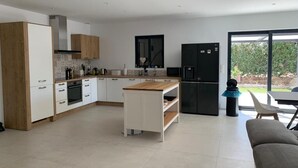 A modern kitchen with white cabinets, a wooden countertop, and a black refrigerator. - Modern air-conditioned architect designed villa with private pool  (Le Cannet-des-Maures)