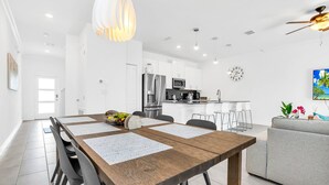 A modern kitchen with white cabinets, stainless steel appliances, and a dining area with a wooden table and chairs.