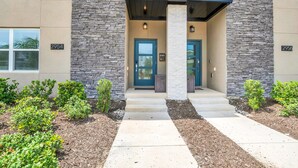 A modern building with stone and stucco exterior, numbered 2954 and 2956, featuring a central entrance with steps and a covered porch.
