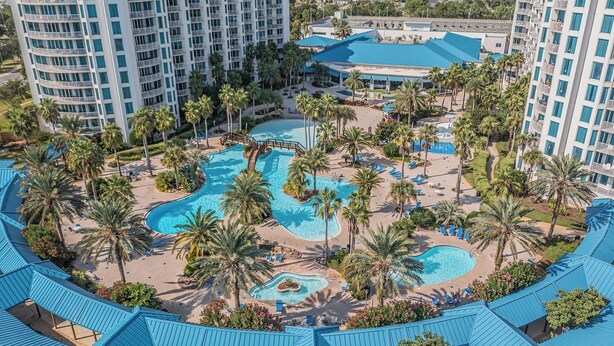 Un resort con varias piscinas, palmeras y un edificio grande con techo azul.